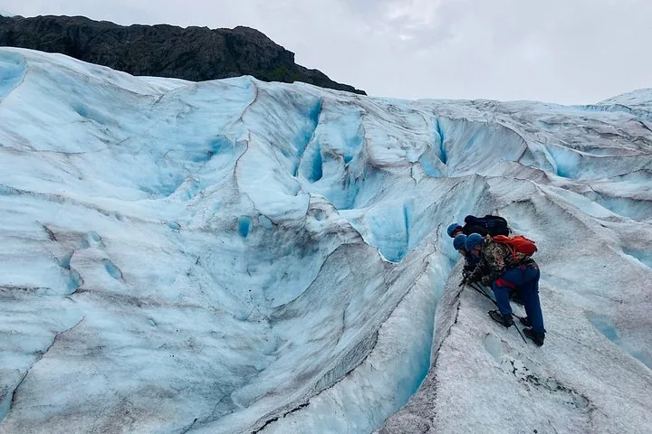 Bergsteiger, die vorsichtig einen steilen, vereisten Hang auf einem Gletscher überqueren.